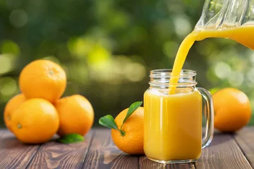Tuinposter orange juice pouring in glass © alter_photo