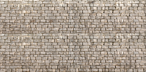 Panoramic background of wide beige brick or stone wall texture. Home or office design backdrop