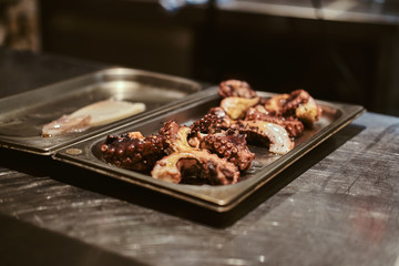 Metal plate with fried octopus and peace of marinated calamari.