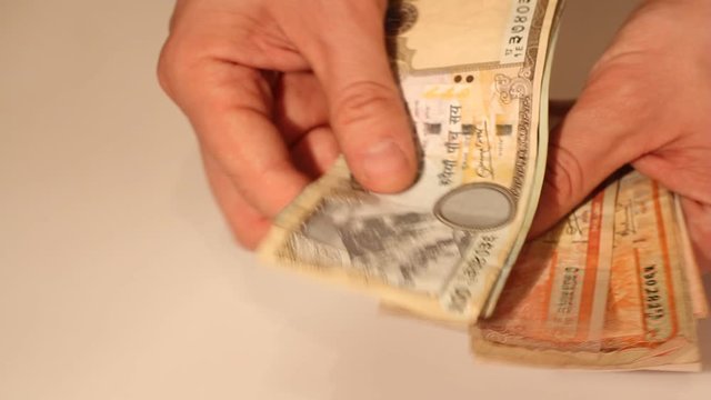 Man's hands counting Nepalese Rupee banknotes. National Currency of Nepal (NPR)