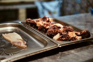 Metal plate with fried octopus and peace of marinated calamari.