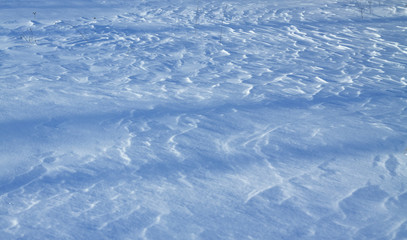 Snow-white snow and the earth sheltered by it. Countryside and snowfall. Winter dunes and mountains of snowflakes. Stock background.
