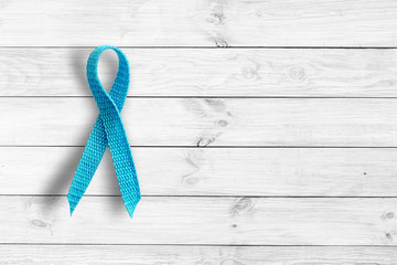 Blue ribbon on light wooden background banner representing an annual event during the month of...