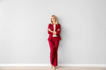 Beautiful stylish businesswoman near light wall