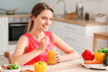 Young woman drinking healthy juice in kitchen. Diet concept