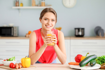 Young woman drinking healthy juice in kitchen. Diet concept