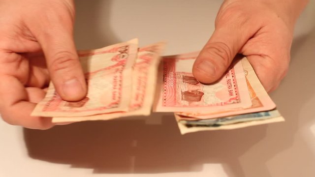 Man's hands counting Nepalese Rupee banknotes. National Currency of Nepal (NPR)