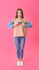 Beautiful young woman with photo camera on color background