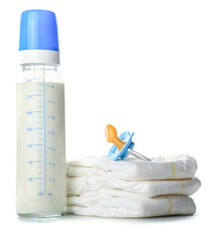 Bottle of milk for baby with pacifier and diapers on white background