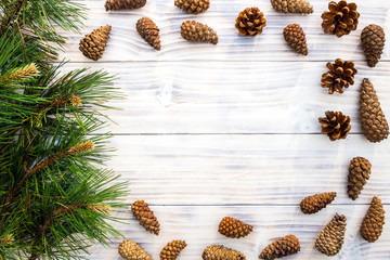 Fir cones with pine branch on white wooden background.