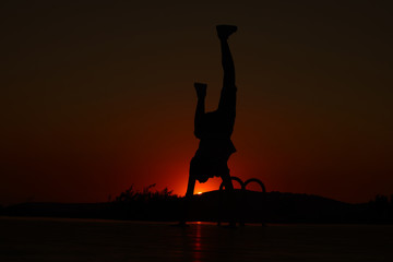 Plakat silhouette of a man jumping on the beach at sunset
