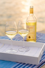 Sunset view of two wine glasses and bottle of white wine on the background of Kotor bay, Montenegro.