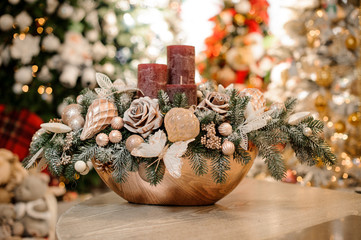Golden vase with christmas decor composition of flowers, toys and three candles