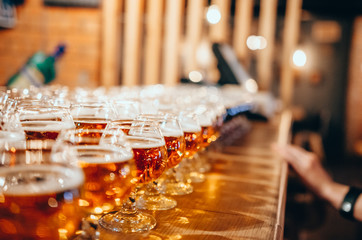 Glasses of light beer on wooden bar counter. Bar on background
