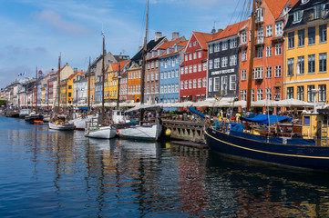 Fototapeta na wymiar Famous Nyhavn pier with colorful facades of old houses and vintage ships in Copenhagen, capital of Denmark. Summertime in the fantastic city of Copenhagen