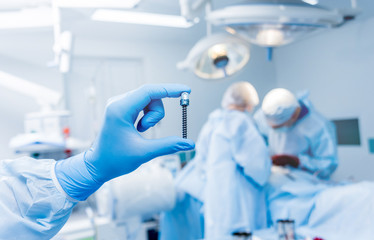 Spinal surgery. Surgeon show polyaxial screw in operating room with surgery equipment. Laminectomy....