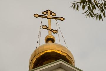 The bulbous spire of the Russian Orthodox Church. Gold domes and an eight-pointed cross. Facing east. Day overcast.