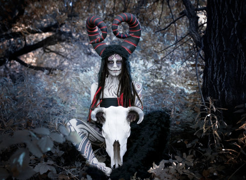 Art photo - demon faun in a fairy forest with a large cow-horned skull between his legs