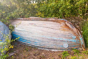 daylight. blue boat is turned upside down. paint faded in the sun.
