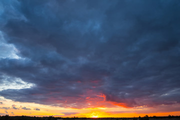 Fototapeta na wymiar dramatic sunset over the prairies, dark dense clouds and red evening sun