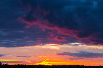 Fototapeta na wymiar dramatic sunset over the prairies, dark dense clouds and red evening sun