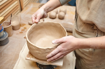 Woman's hands molding clay with sponge. Potter making ceramic pot in pottery workshop