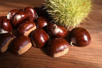 Closeup on chestnuts and curly on wooden background. Raw chestnuts for Christmas.
