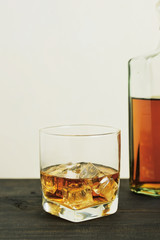 glass of whiskey with ice cubes on wooden table