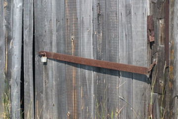 Image of an old wooden gate with a rusty lock and eyelet