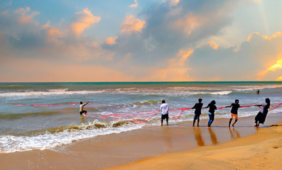 Fototapeta na wymiar Wadduwa Sri Lanka - November 2018: Local fishermen pull a net from the ocean.