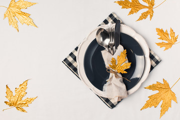 Autumn thansgiving and halloween tableware flat lay with plate and leaves on white cloth background