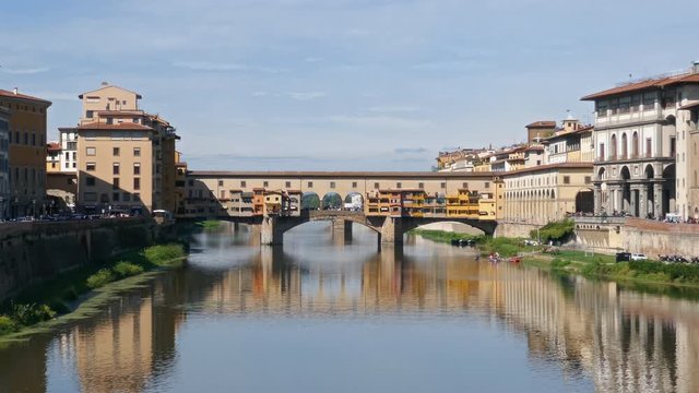 Walking in front of Ponte Vecchio, medieval stone bridge over of Arno river at clear summer day in Florence, Italy.