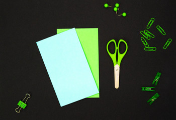Educational composition, stationery. Green stationery and green notebook on a black background. Flat lay, top view, copy space