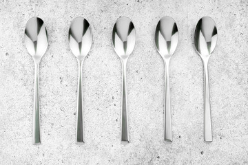 Cutlery. Spoons on a light concrete background. Flat lay, top view, copy space.