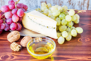 Grapes, some cheese and olive oil for snack on the wooden table.
