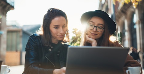 Friends communication using digital tablet together. Two girls hipster travels in Barcelona sitting in cafe. Business startup friendship concept. Internet technology working process project copy space
