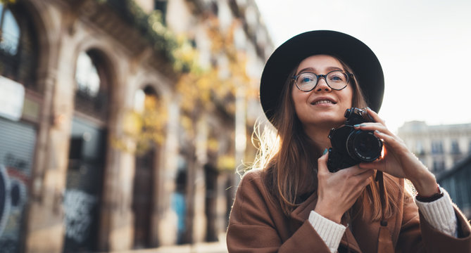 Photographer take photo on retro camera. Tourist portrait girl in hat travels in Barcelona holiday. Sunlight flare street in europe city. Traveler hipster shooting architecture, copy space mockup