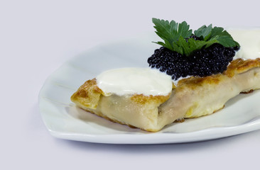 Stuffed pancake with black caviar and sour cream.