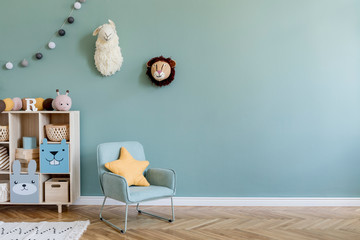 Interior design of scandinavian childroom with wooden cabinet, mint armchair, a lot of plush and wooden toys. Eucalyptus color of background walls. Plush animal head on the wall. Template Copy space
