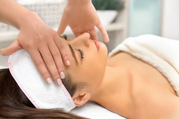 Fototapeta na wymiar spa, resort, beauty and health concept - beautiful woman in spa salon getting face treatment