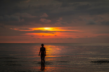 standing in the asian sea at sunset