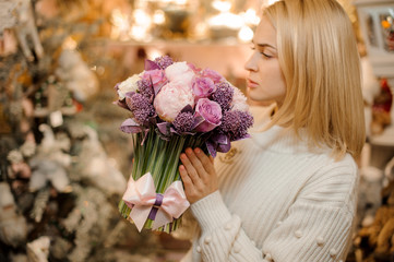Beautiful woman holding a bouquet of tender pink and purple color flowers with green stalks