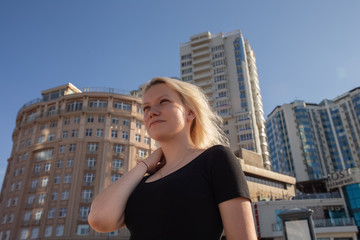Fototapeta na wymiar Blonde girl on the background of high-rise buildings