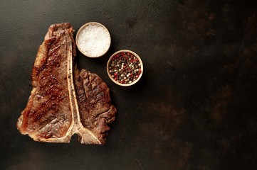 Grilled T-bone steak on a stone table. With rosemary and spices. Top view with copy space.