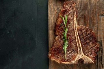 Grilled T-bone steak on a stone table. With rosemary and spices.