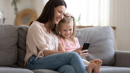 Happy mother and little daughter looking at phone screen together