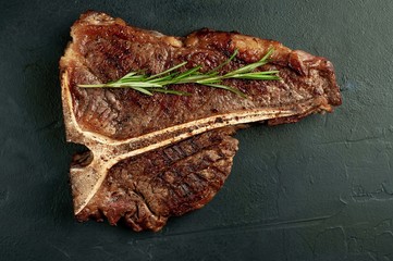 Grilled T-bone steak on a stone table. With rosemary and spices. 
