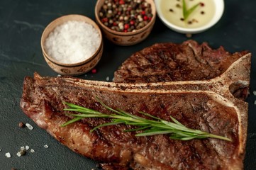 Grilled T-bone steak on a stone table. With rosemary and spices. 