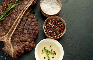 Grilled T-bone steak on a stone table. With rosemary and spices. Top view with copy space.