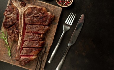 Grilled T-bone steak on a stone table. With rosemary and spices. Top view with copy space.